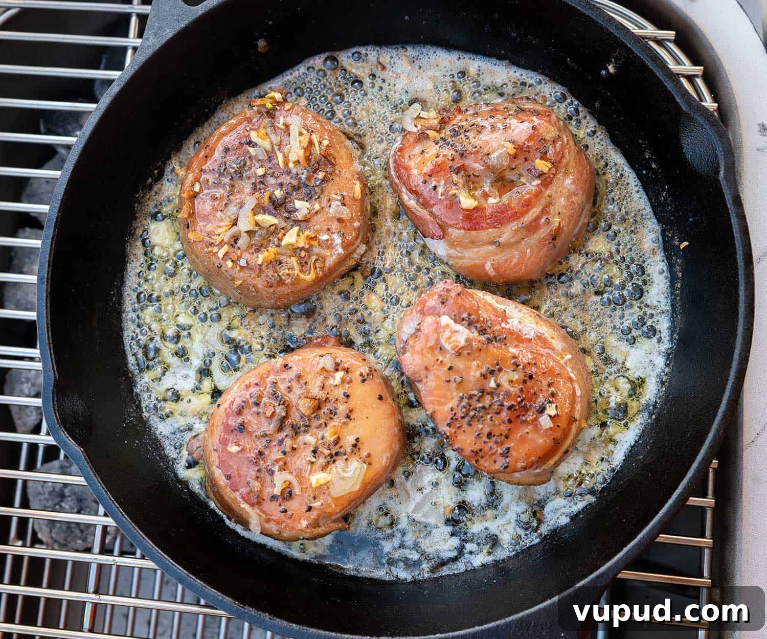 Whiskey-Peach Glazed Bacon-Wrapped Pork Loin Filets 7 overhead shot of pork loin filets in cast iron skillet on grill.
