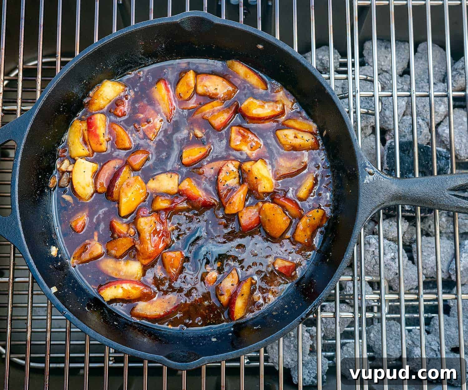 Whiskey-Peach Glazed Bacon-Wrapped Pork Loin Filets 8 overhead shot of barbecue peaches in cast iron skillet on grill.
