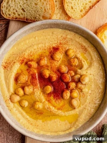 A bowl of hummus topped with chickpeas and paprika.