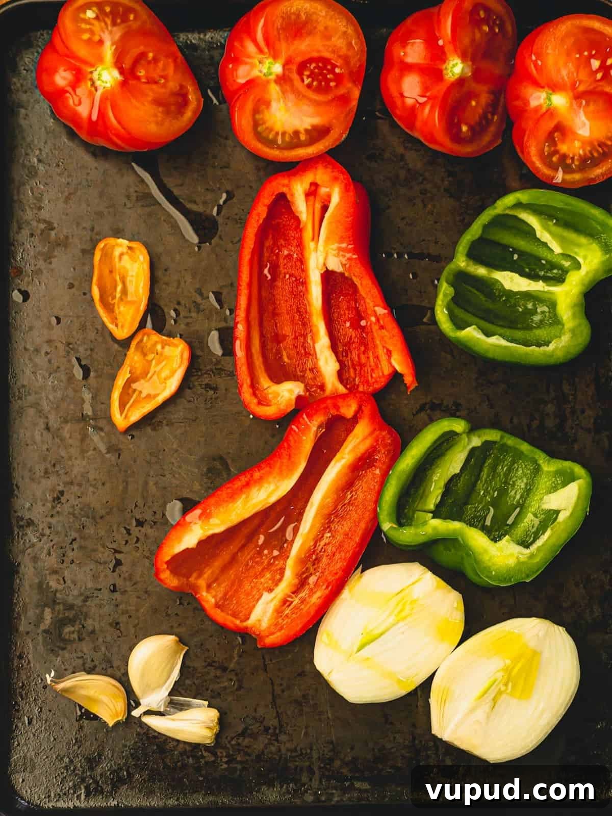 Smoky Roasted Tomato and Habanero Salsa Recipe 5 A sheet pan filled with bell peppers, yellow onion and tomatoes cut in half and drizzled with olive oil.