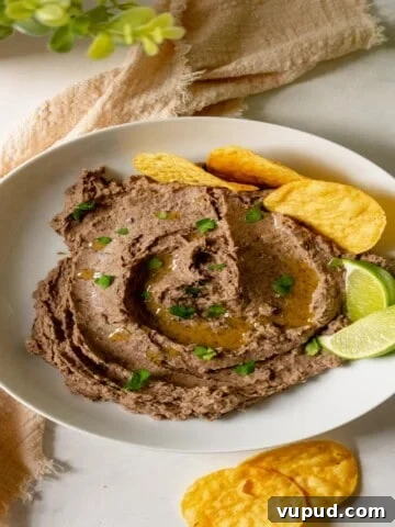 a white bowl filled with avocado black bean dip and garnished with lime wedges