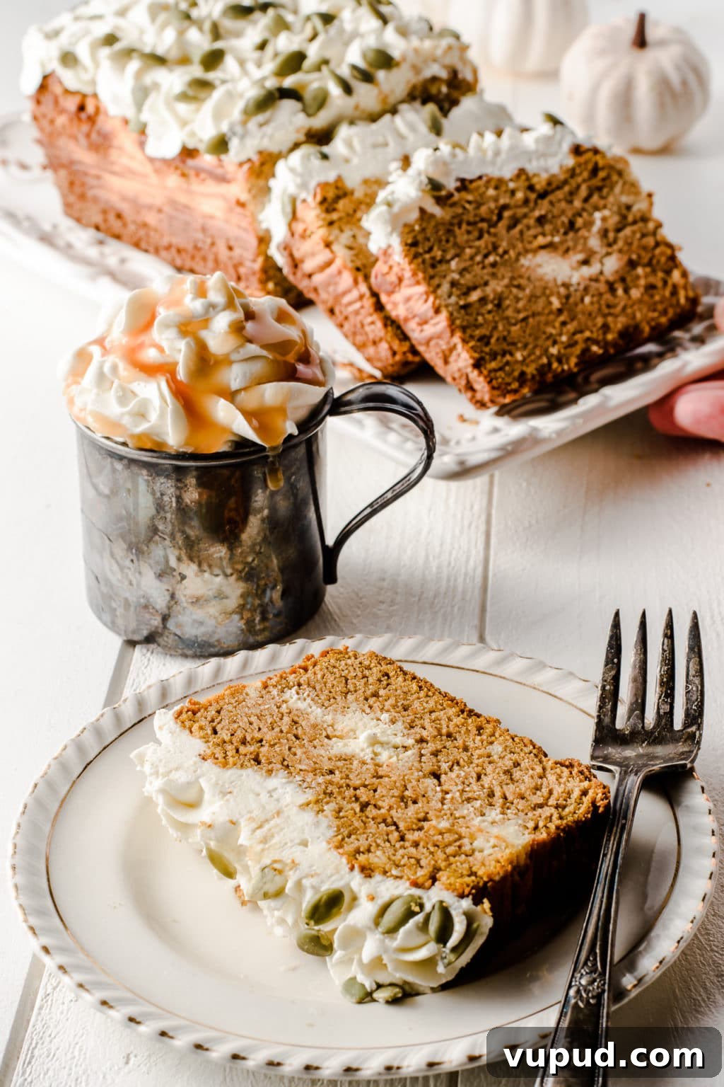 Low-Carb Spiced Pumpkin Bread Stuffed with Cheesecake 12 A slice of low carb pumpkin bread on a plate, with a hot beverage loaded with whipped cream and caramel sauce.
