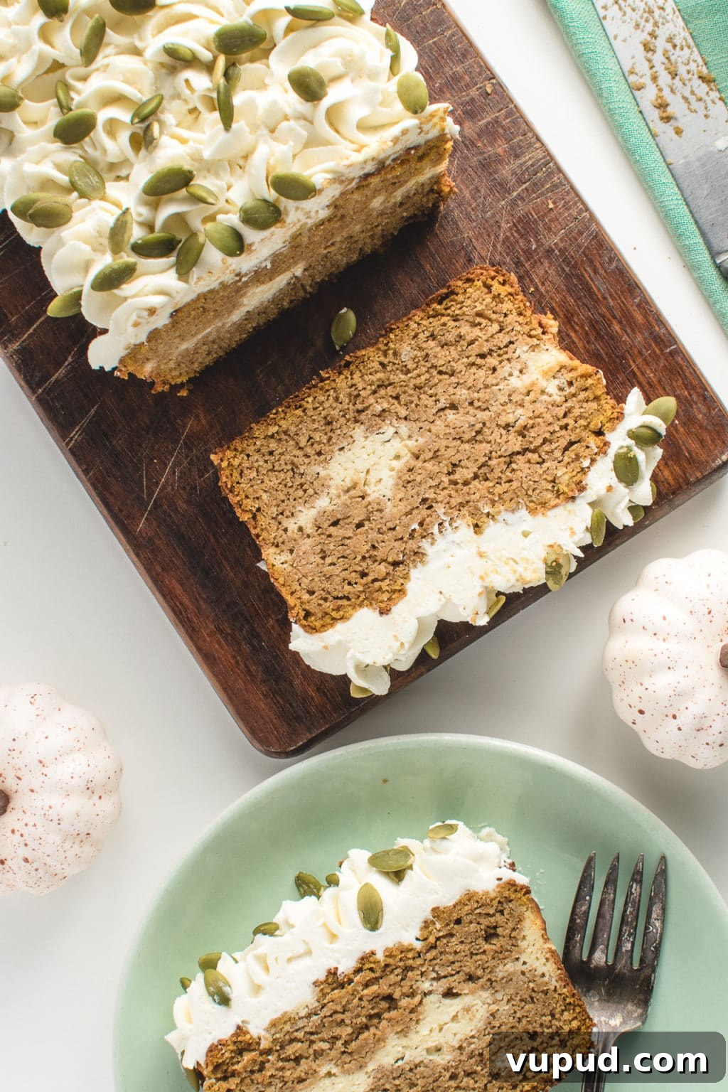 Low-Carb Spiced Pumpkin Bread Stuffed with Cheesecake 7 Overhead shot showing a pumpkin loaf on a cutting board, with a slice on a plate next to it.
