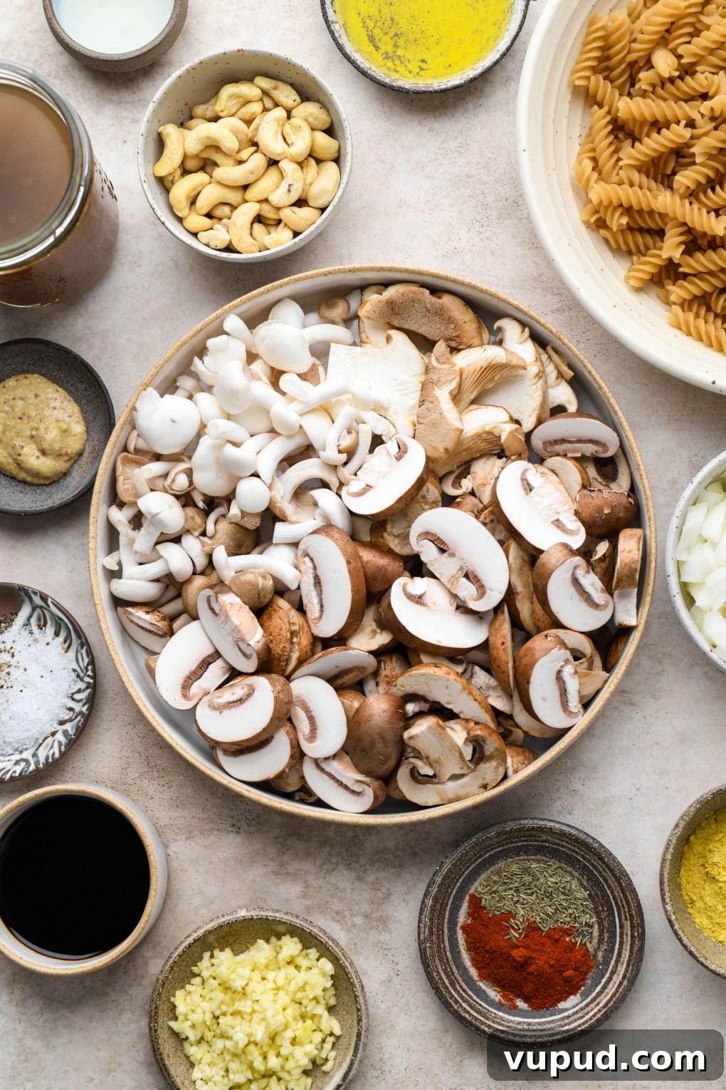 Cashew Cream Mushroom Stroganoff (Gluten-Free) 4 Ingredients for vegan mushroom stroganoff in various ceramic bowls and dishes on a light brown background.