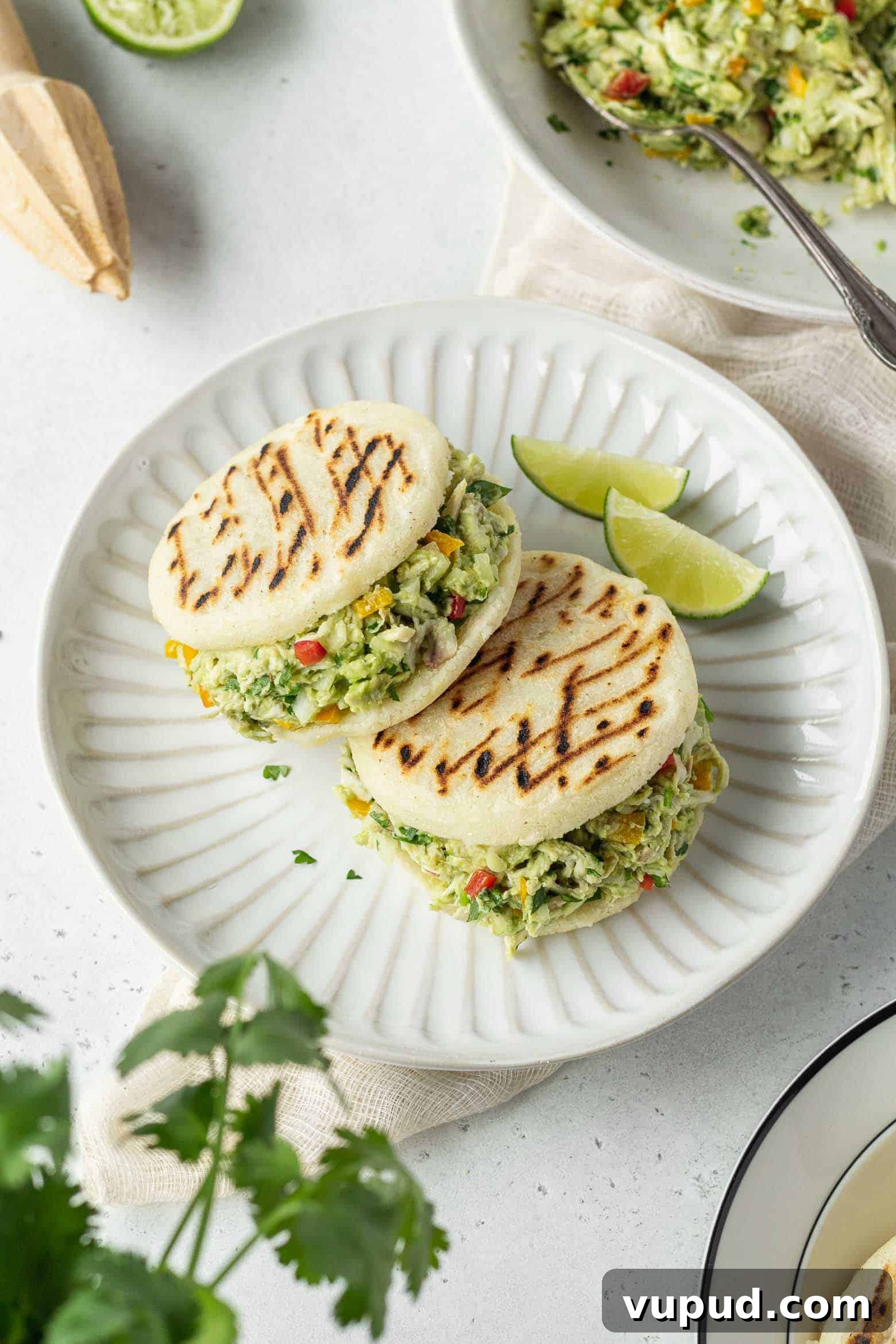 Reina Pepiada Arepa: Venezuelan Chicken & Avocado Recipe 2 Two reina pepiada on a plate with lime wedges