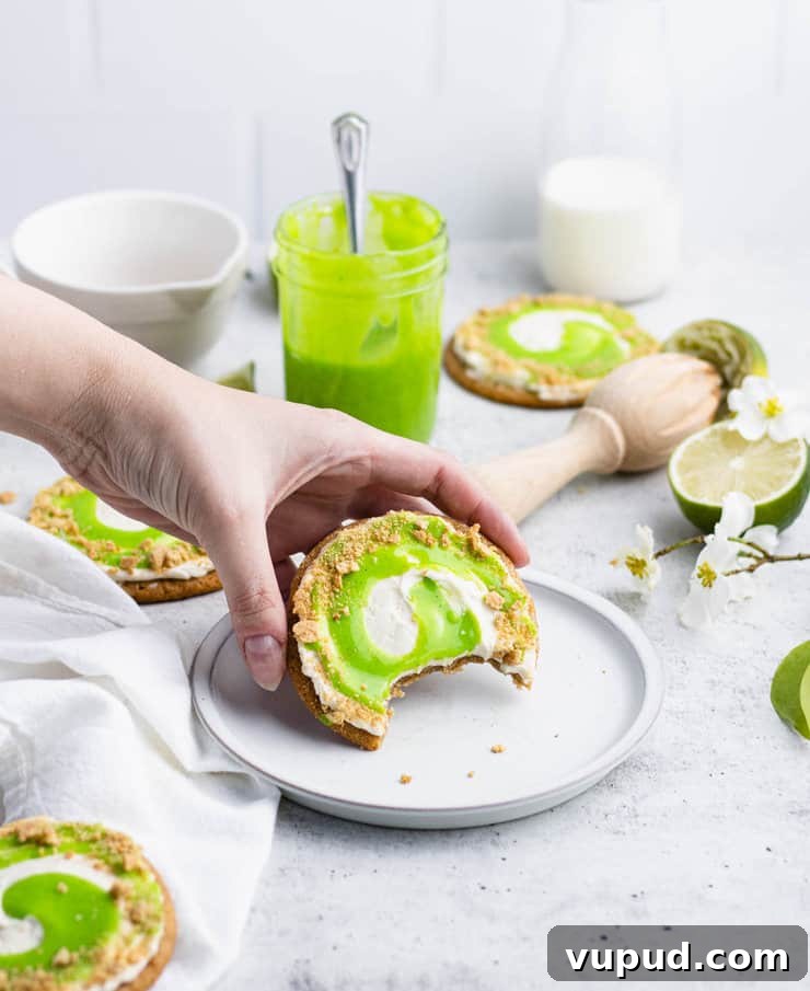 Zesty Key Lime Cookies Recipe: Tangy Citrus Cookie Delight 2 Hand picking up a graham cracker cookie frosted with Russian buttercream and a swirl of lime curd.