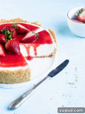 sliced cheesecake with strawberries on top and a strawberry drip down the sliced side