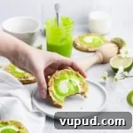 Hand picking up a graham cracker cookie frosted with Russian buttercream and a swirl of lime curd.