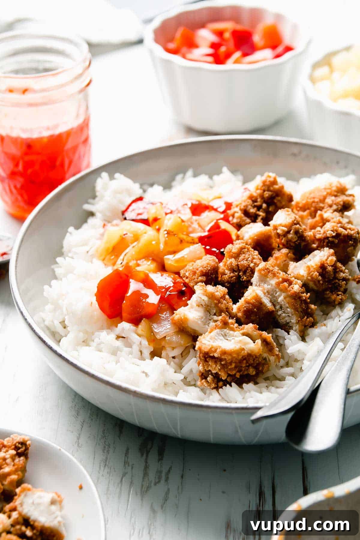 Gluten-Free Sweet Fire Chicken Recipe — Panda Express Copycat 4 A bowl of steamed rice topped with golden brown chunks of breaded chicken and bright red bell pepper and yellow pineapple in sweet chili sauce.