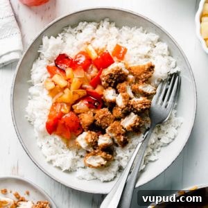 Gluten-Free Sweet Fire Chicken Recipe — Panda Express Copycat 6 A shallow bowl filled with diced breaded chicken, red bell peppers, onion, and pineapple in sweet fire sauce atop a bed of rice.