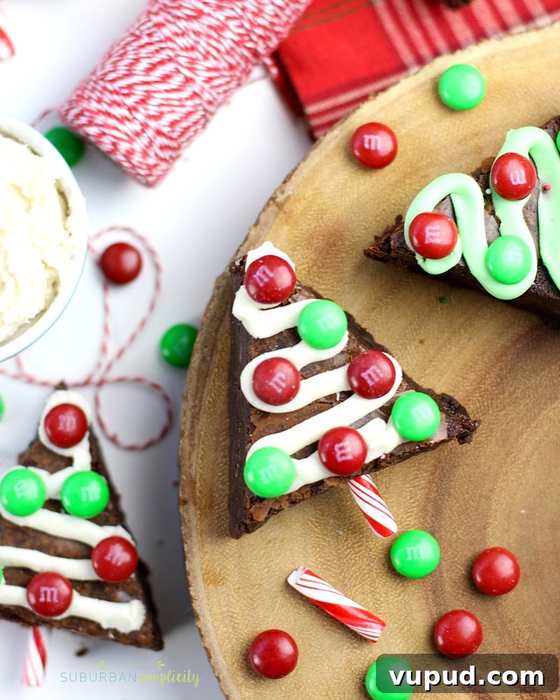 27+ Festive Christmas Finger Food Appetizers for Holiday Parties 25 Brownies cut in the shape of Christmas trees with ribbons of frosting and M&M ornaments.