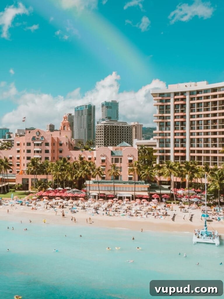 The Royal Hawaiian Hotel: Historic Luxury in Waikiki Beach 2 The Royal Hawaiian resort beachfront area in Waikīkī by the ocean with beach chairs and umbrellas and a catamaran