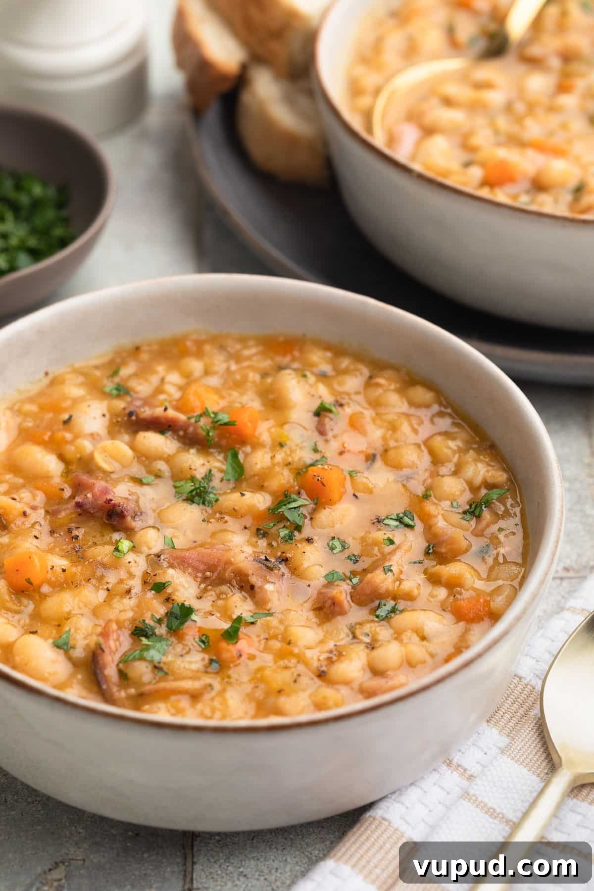 Classic Ham and Bean Soup Recipe for Comforting Weeknight Meals 2 ham and bean soup in an ivory ceramic bowl garnished with fresh parsley