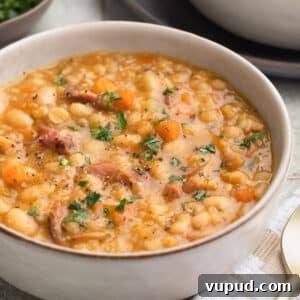 Classic Ham and Bean Soup Recipe for Comforting Weeknight Meals 15 ham and bean soup in an ivory ceramic bowl garnished with fresh parsley