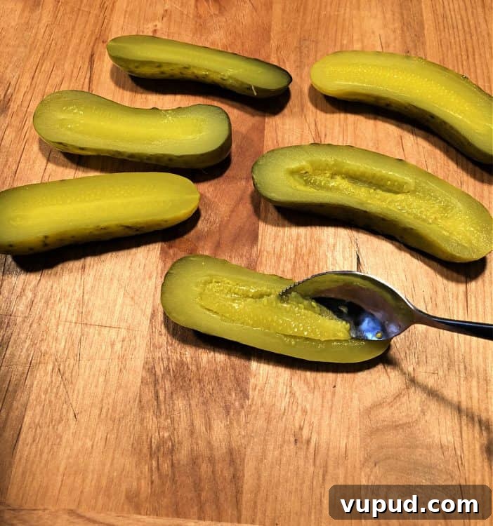 Tuna Salad Stuffed Avocado Boats for Quick Lunch 3 scooping middle part from pickles