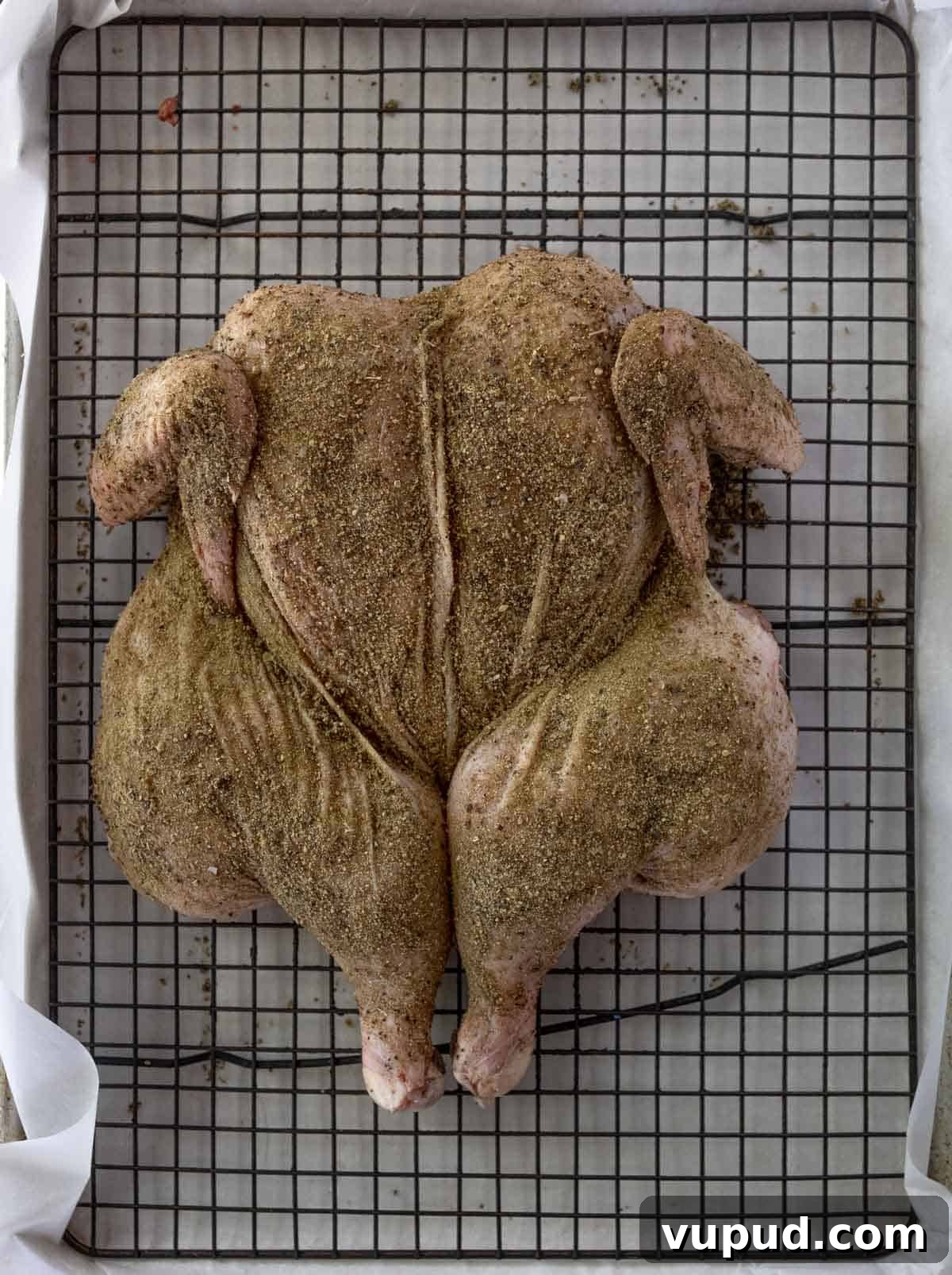 Grilled Spatchcocked Dry-Brined Chicken for Crispy, Juicy Results 5 A spatchcocked chicken on a sheet pan with a wire rack.
