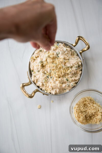 10-Minute Crab Dip with Crispy Tortilla Crust 13 hand sprinkling tortilla crumbs on hot crab dip