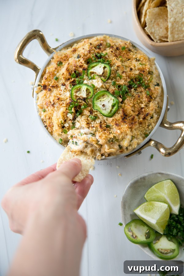 10-Minute Crab Dip with Crispy Tortilla Crust 17 hand dipping tortilla in baked crab dip