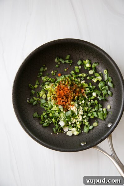 10-Minute Crab Dip with Crispy Tortilla Crust 9 scallions garlic and jalapeno in a skillet