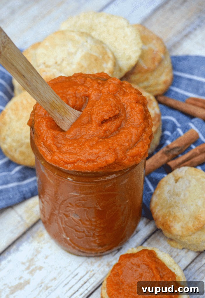 a wooden spoon sticking out a glass jar filled with homemade pumpkin butter