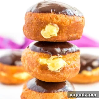 Boston Cream Donuts: Where to Find & How They're Made in Boston 14 Stack of three Boston Cream Donuts on top of each other, more donuts in background.