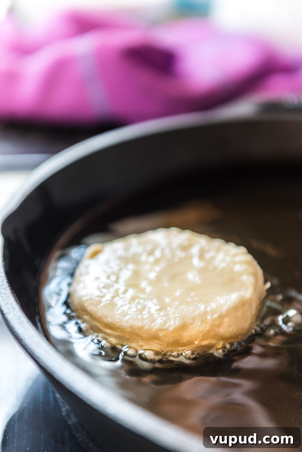 Boston Cream Donuts: Where to Find & How They're Made in Boston 4 Refrigerated biscuit being fried in a cast iron pan to make donuts.