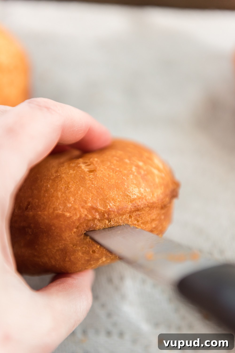 Boston Cream Donuts: Where to Find & How They're Made in Boston 8 Paring knife being used to cut a slit in the side of a donut to add filling.