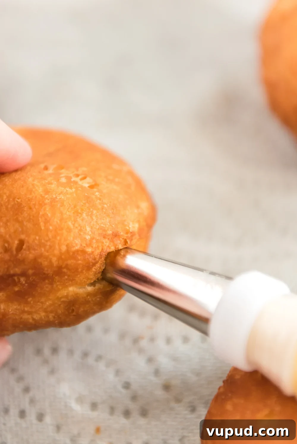 Boston Cream Donuts: Where to Find & How They're Made in Boston 9 Vanilla pastry filling being piped into a cooked donut.