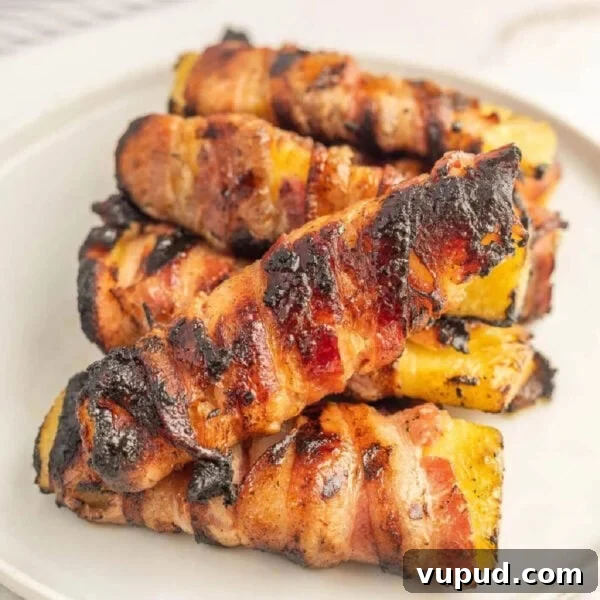 Crispy Pineapple Chicken on the Blackstone Grill: Sweet & Savory Recipe 11 Grilled bacon-wrapped chicken thighs with charred grill marks on a white plate