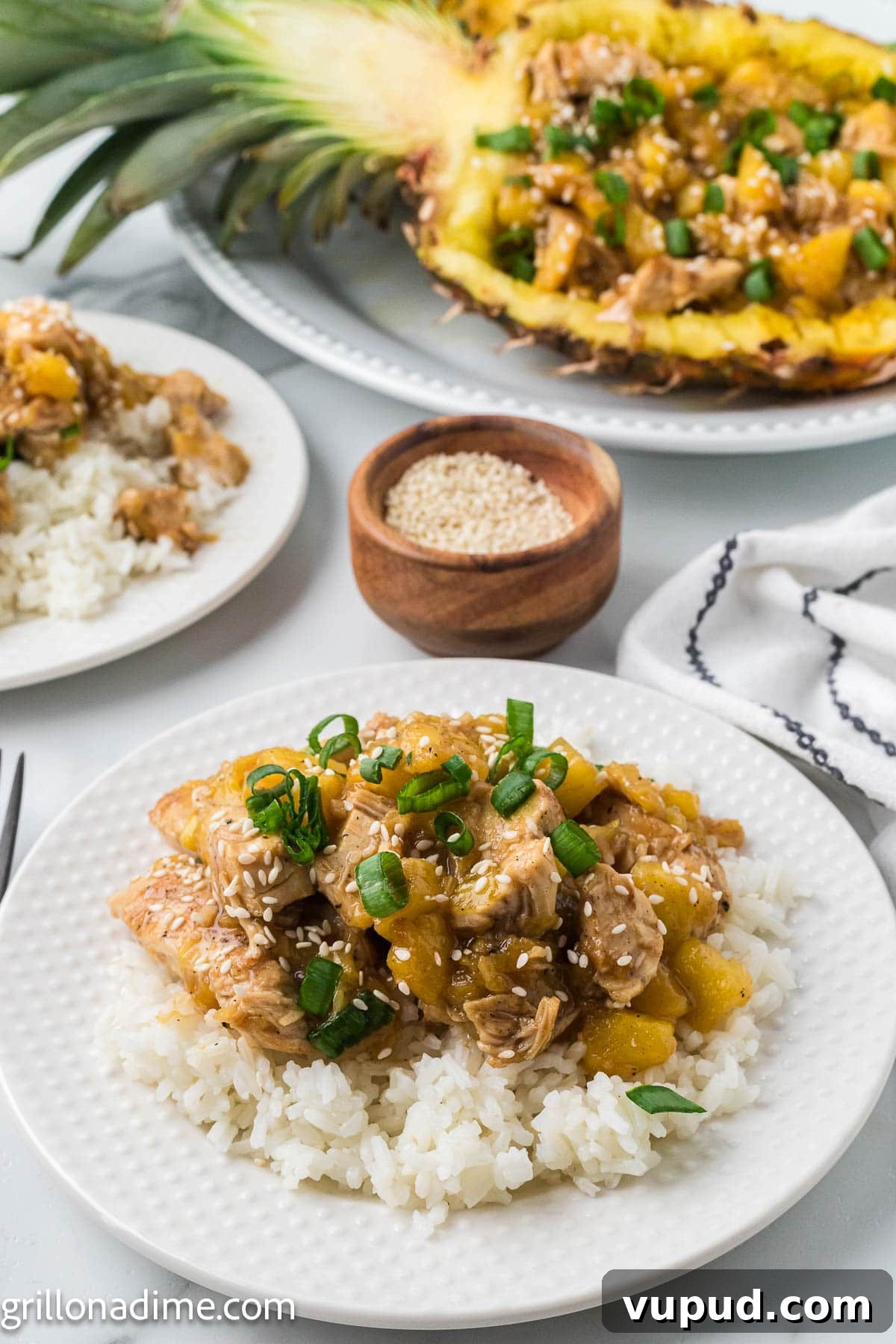 Crispy Pineapple Chicken on the Blackstone Grill: Sweet & Savory Recipe 8 Pineapple chicken on a plate over white rice and large pineapple in the background with pineapple chicken