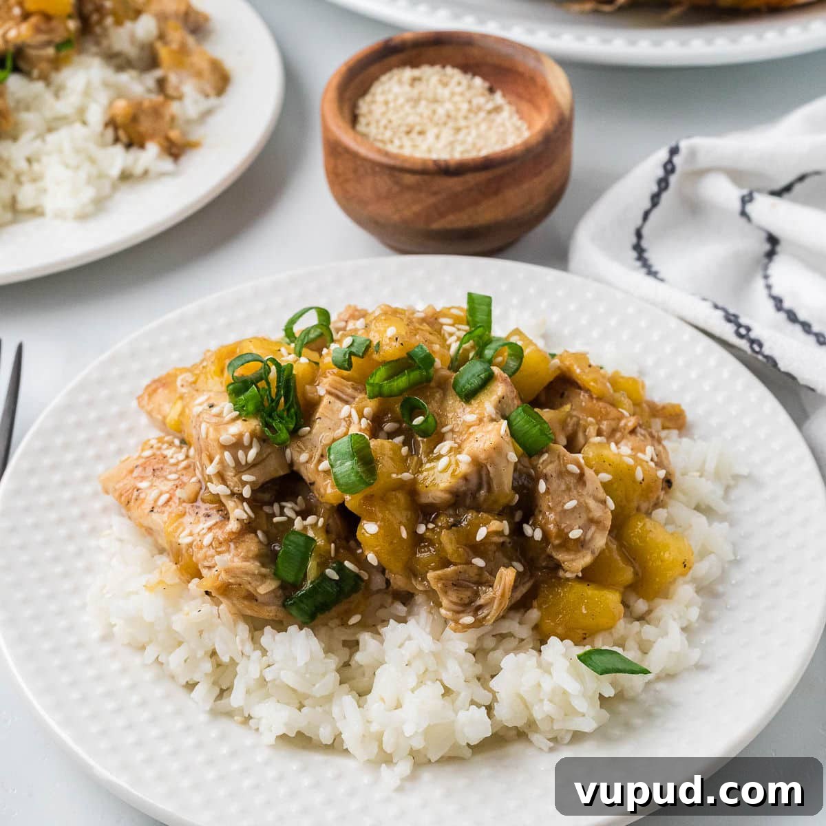 Crispy Pineapple Chicken on the Blackstone Grill: Sweet & Savory Recipe 10 A plate of white rice topped with Blackstone pineapple chicken, sliced green onions, and sprinkled with sesame seeds.