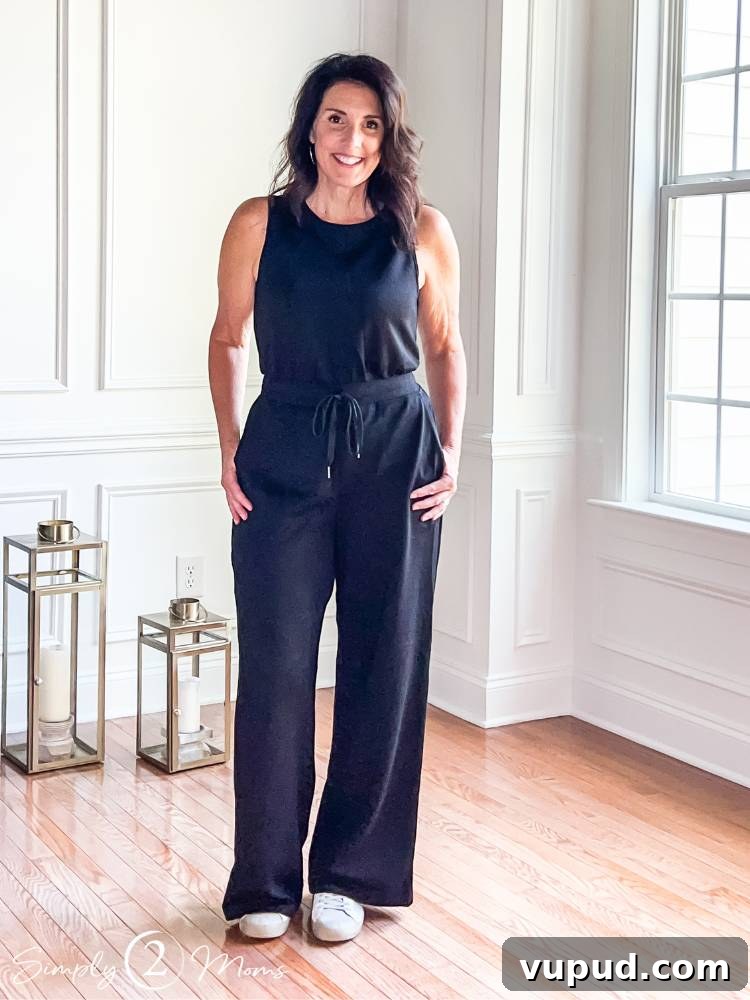 AnnMarie wearing wide leg black one piece jumpsuit with sneakers modeling a travel outfit