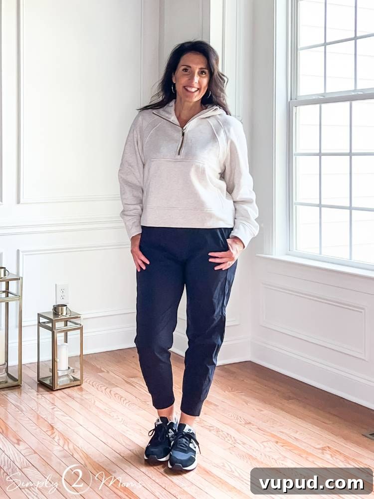 woman standing with hands in both pockets of black joggers and white half zip
