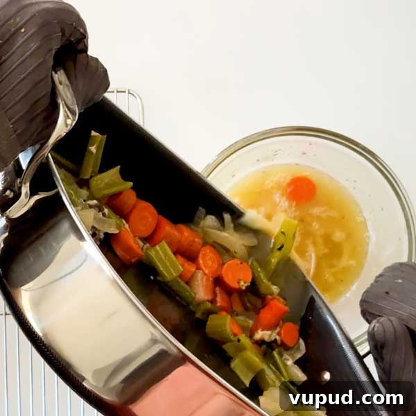Spatchcock Turkey with Gluten-Free Gravy Cooked in HexClad Pan 14 Pouring the vegetables and drippings from the roasting pan into a mixing bowl.