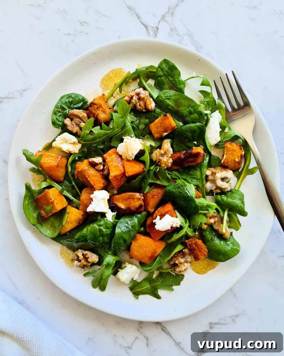 Roasted Pumpkin, Spinach & Goat Cheese Salad Rezept 7 Overhead view of salad on a white plate with a fork