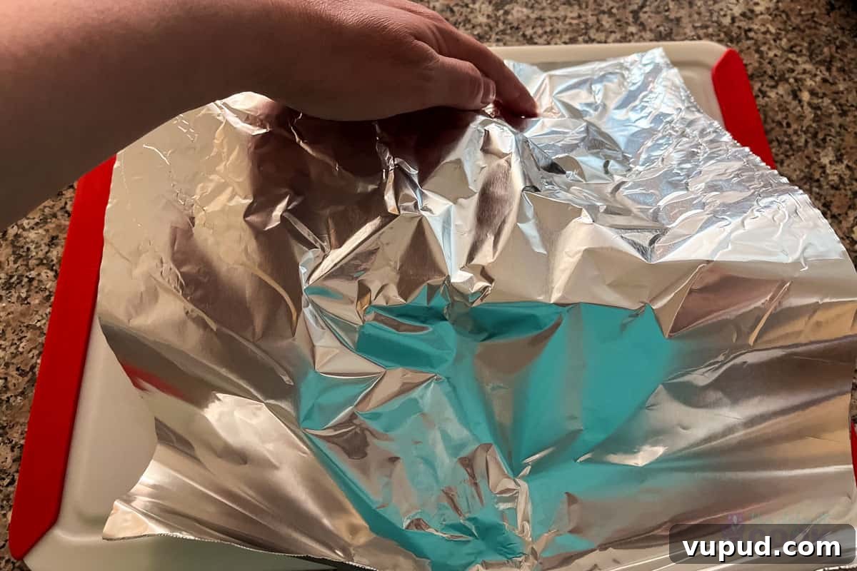 Perfectly Tender Sous Vide Prime Rib Roast Recipe 11 Foil covering a roast on a cutting board.