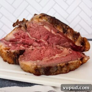 Perfectly Tender Sous Vide Prime Rib Roast Recipe 13 A choice rib roast on a cutting board, sliced open so half has fallen down and the other half is standing.