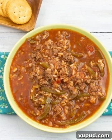 Instant Pot Stuffed Pepper Soup served in a green glass bowl with crackers on the side.