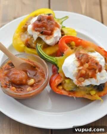 Stuffed bell peppers on a plate topped with sour cream and salsa.