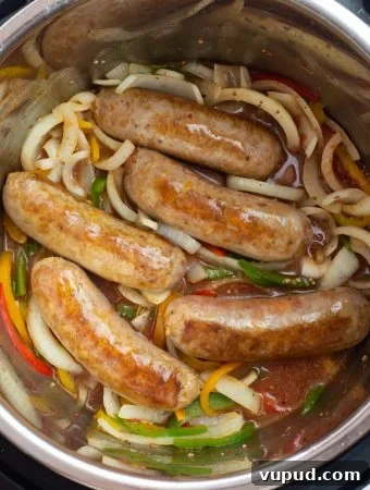Overhead photo of 5 Italian sausages with sliced peppers and onions