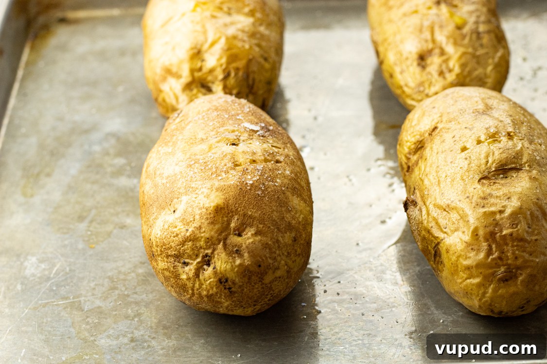 Crispy Oven-Roasted Potatoes with Garlic and Herbs 4 baked potatoes on a baking sheet