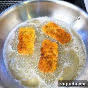 Crispy Homemade Mozzarella Sticks with Marinara Dipping Sauce 9 Mozzarella sticks frying in a pan.