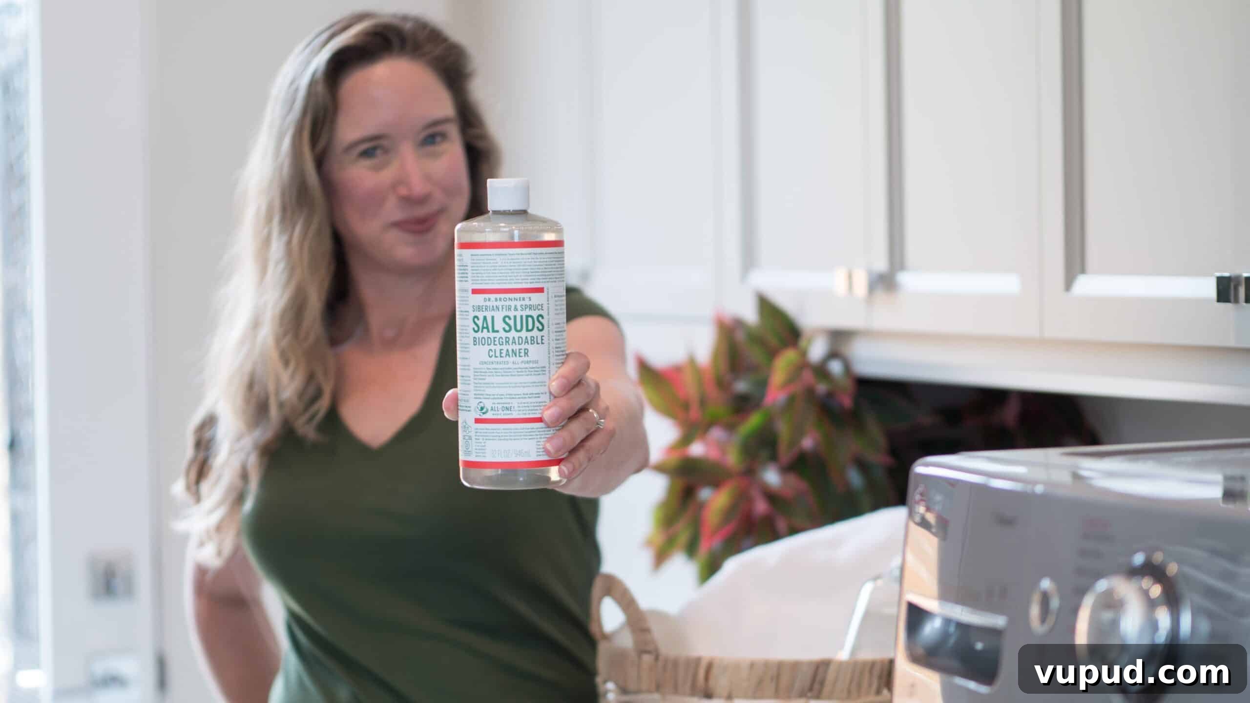 Lisa Bronner holding out a bottle of Sal Suds in her laundry room.