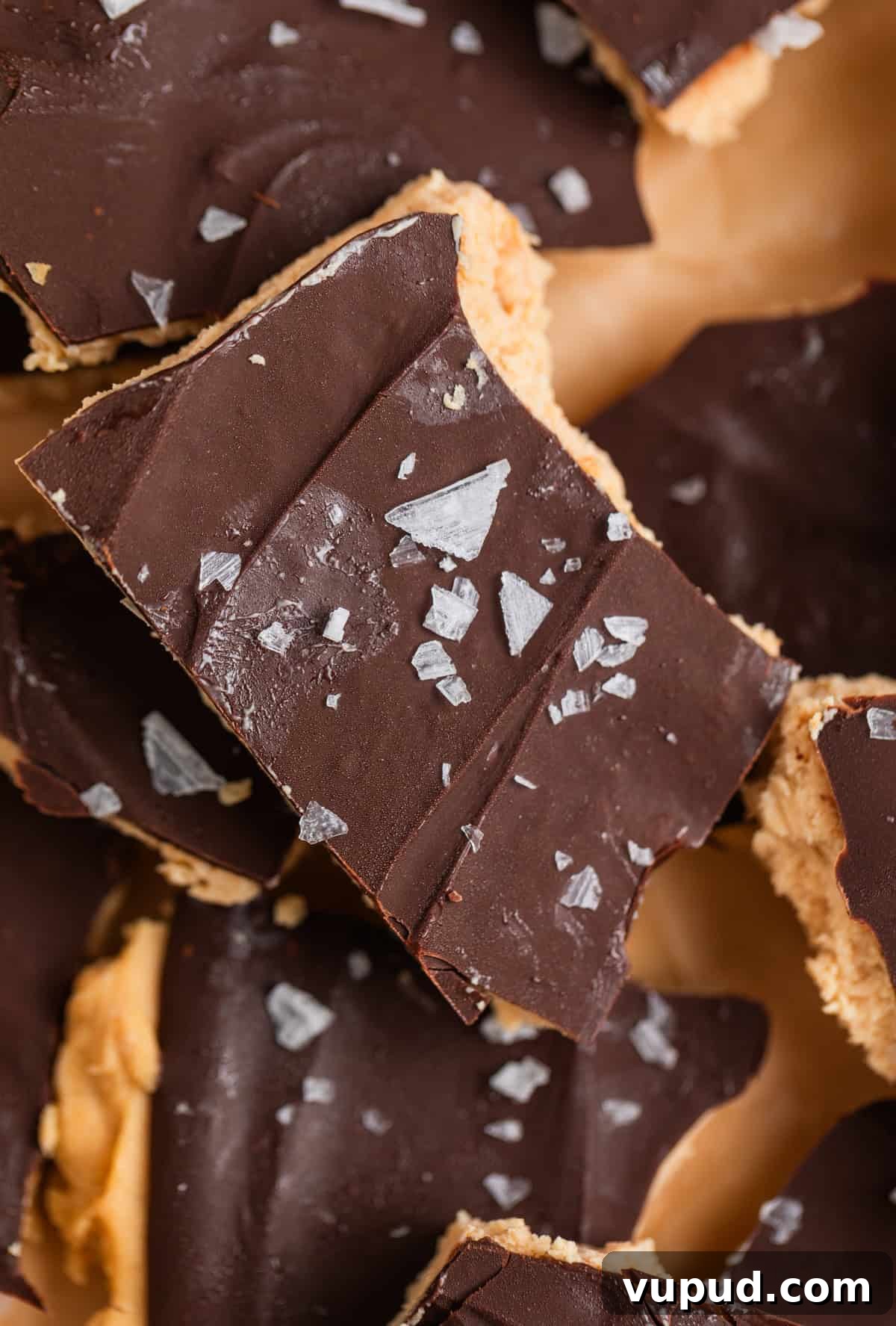 How to Make Creamy Greek Yogurt Bark with Fruit & Nuts 7 Close up of frozen chocolate covered peanut butter yogurt bark scattered on parchment paper.