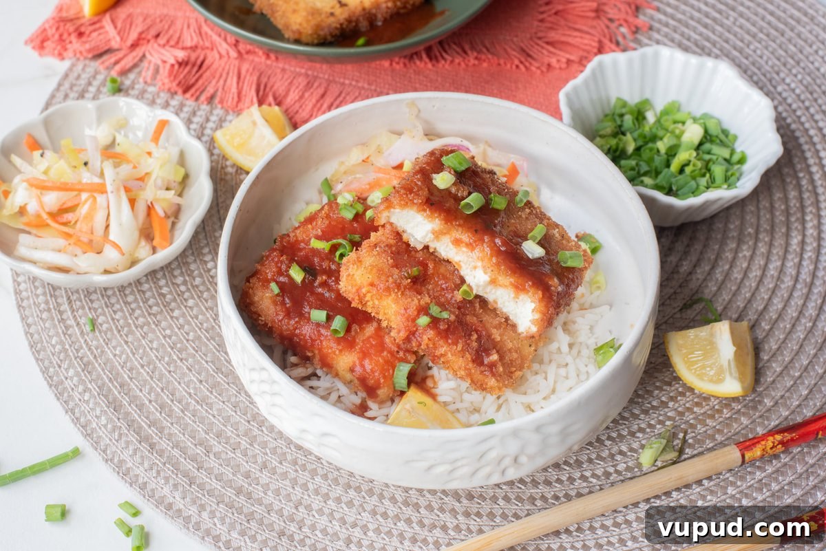 Crispy Tofu Katsu Recipe: Crunchy Plant-Based Cutlets 11 A close up image of tofu katsu served in a bowl over rice.
