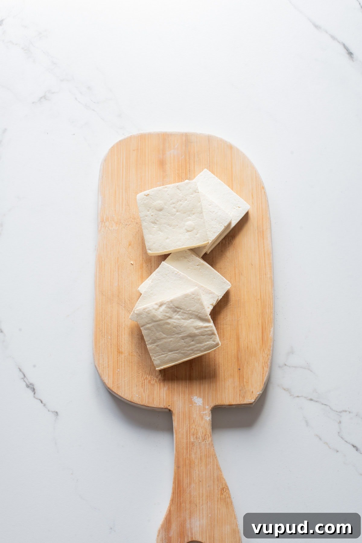Crispy Tofu Katsu Recipe: Crunchy Plant-Based Cutlets 6 An overhead image of tofu cubes on a wooden cutting board.