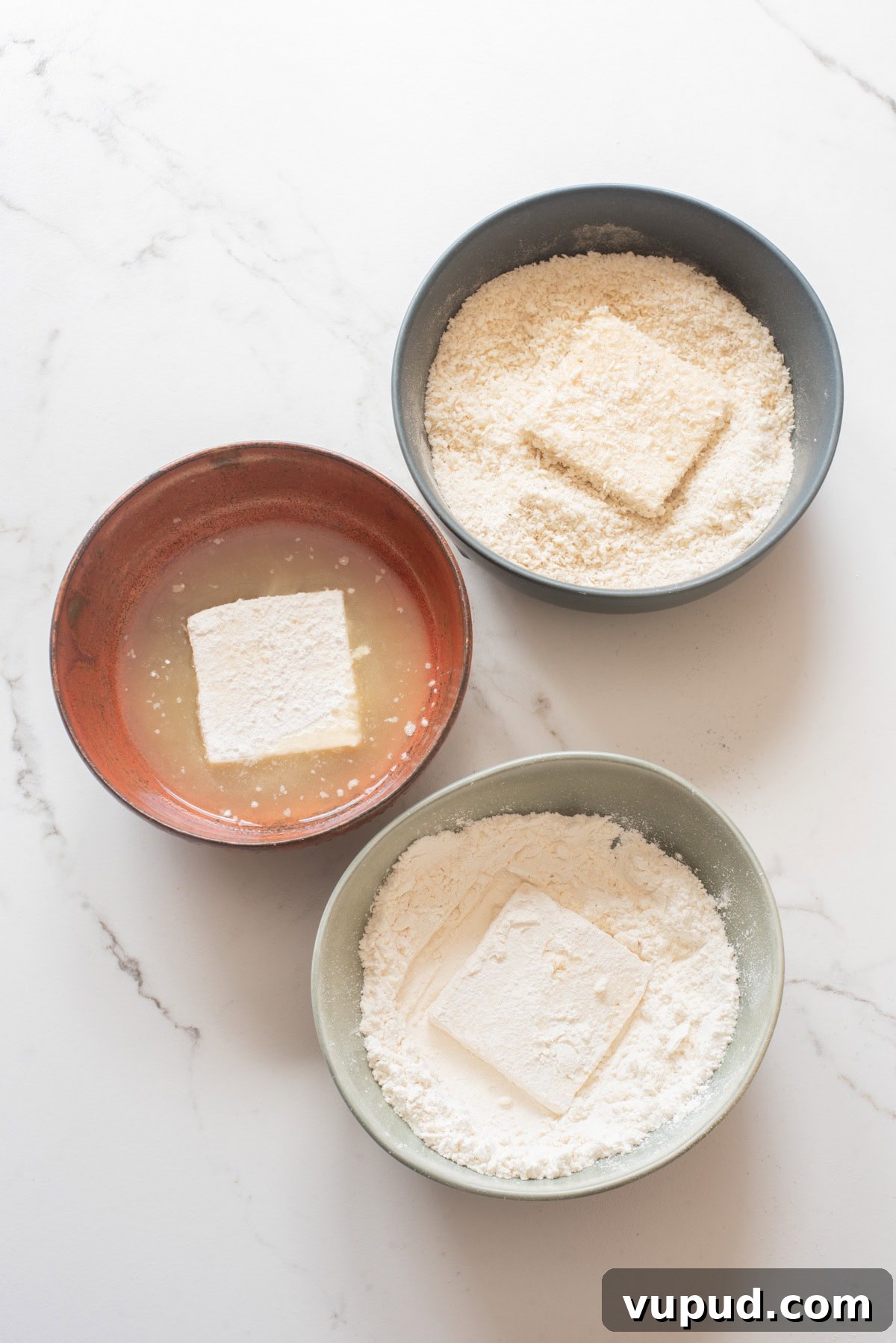 Crispy Tofu Katsu Recipe: Crunchy Plant-Based Cutlets 7 An overhead image of breading the tofu.