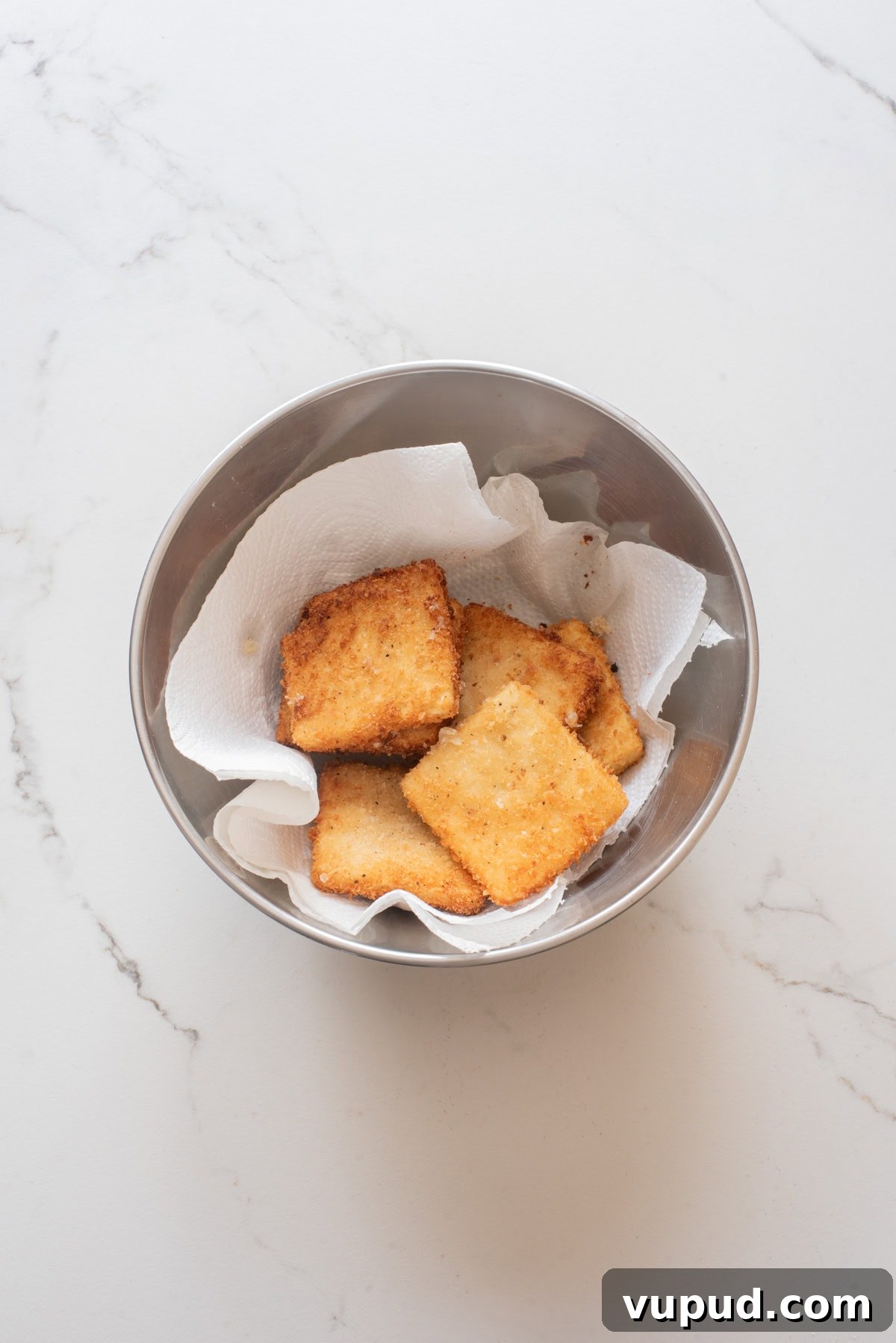 Crispy Tofu Katsu Recipe: Crunchy Plant-Based Cutlets 9 An overhead image of transferring the fried tofu katsu in a bowl lined with paper towels.