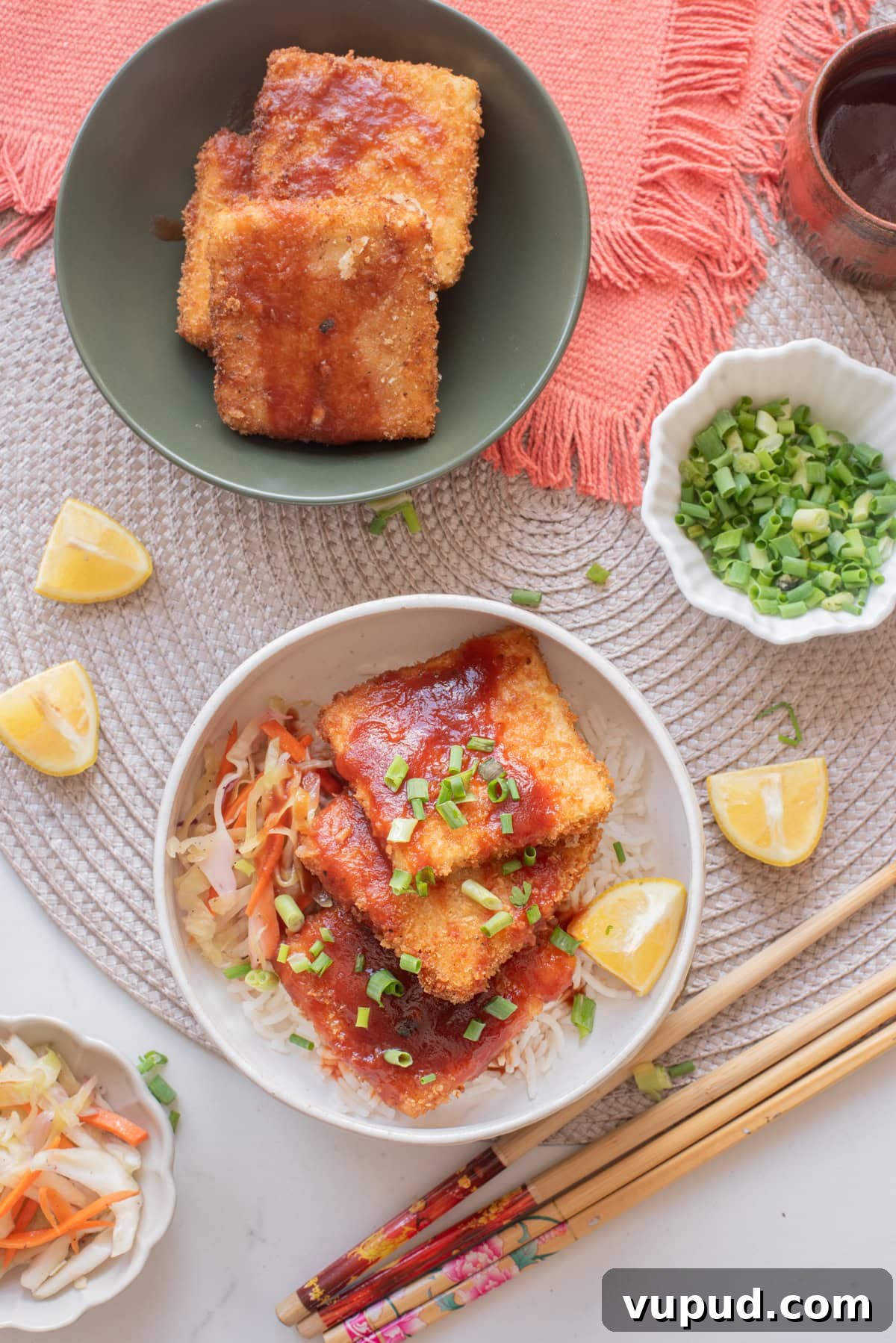 Crispy Tofu Katsu Recipe: Crunchy Plant-Based Cutlets 10 An overhead image of serving the tofu katsu in a bowl over slaw and rice.