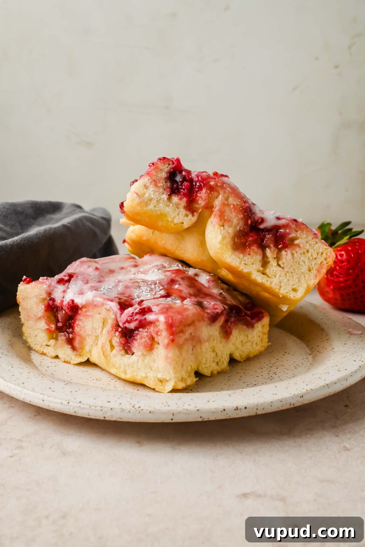 Raspberry Jam Sweet Focaccia Recipe for Soft, Fruity Bread 2 two slices of sweet focaccia with raspberry jam and powdered sugar glaze stacked on serving plate.